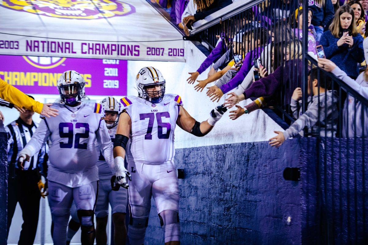 LSU football graduate student offensive tackle Austin Deculus (76) and graduate student Neil Farrell Jr. (92) high five fans Saturday, Nov. 27, 2021, while walking onto the field before LSU's 27-24 win against Texas A&amp;M at Tiger Stadium in Baton Rouge, La.