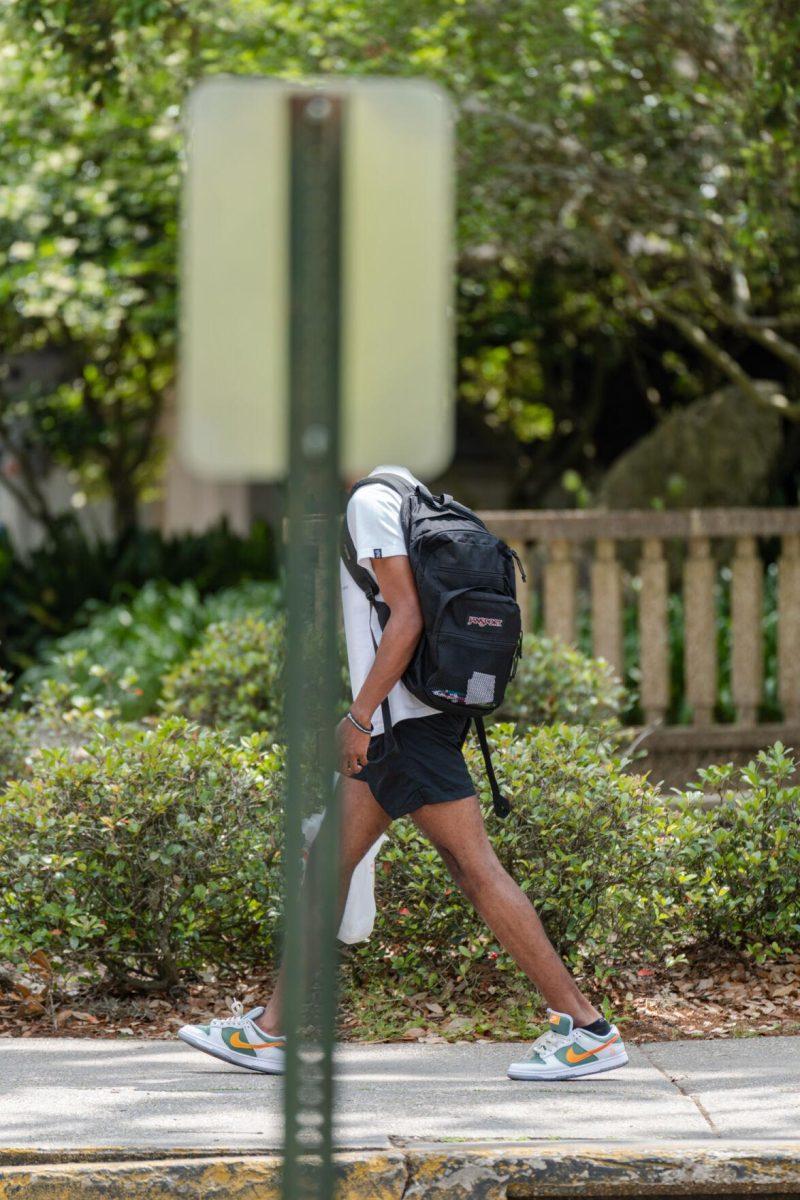 A sign replaces the walker&#8217;s head for a split second on Thursday, April 21, 2022, in front of the LSU Student Union on Highland Road in Baton Rouge, La.