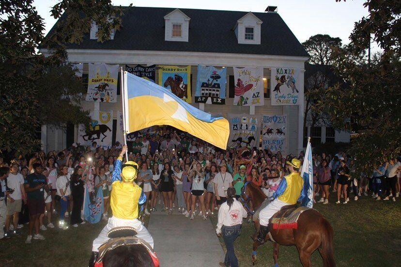 Students wave a Sigma Chi flag in front of Derby Days participants at the opening ceremony.