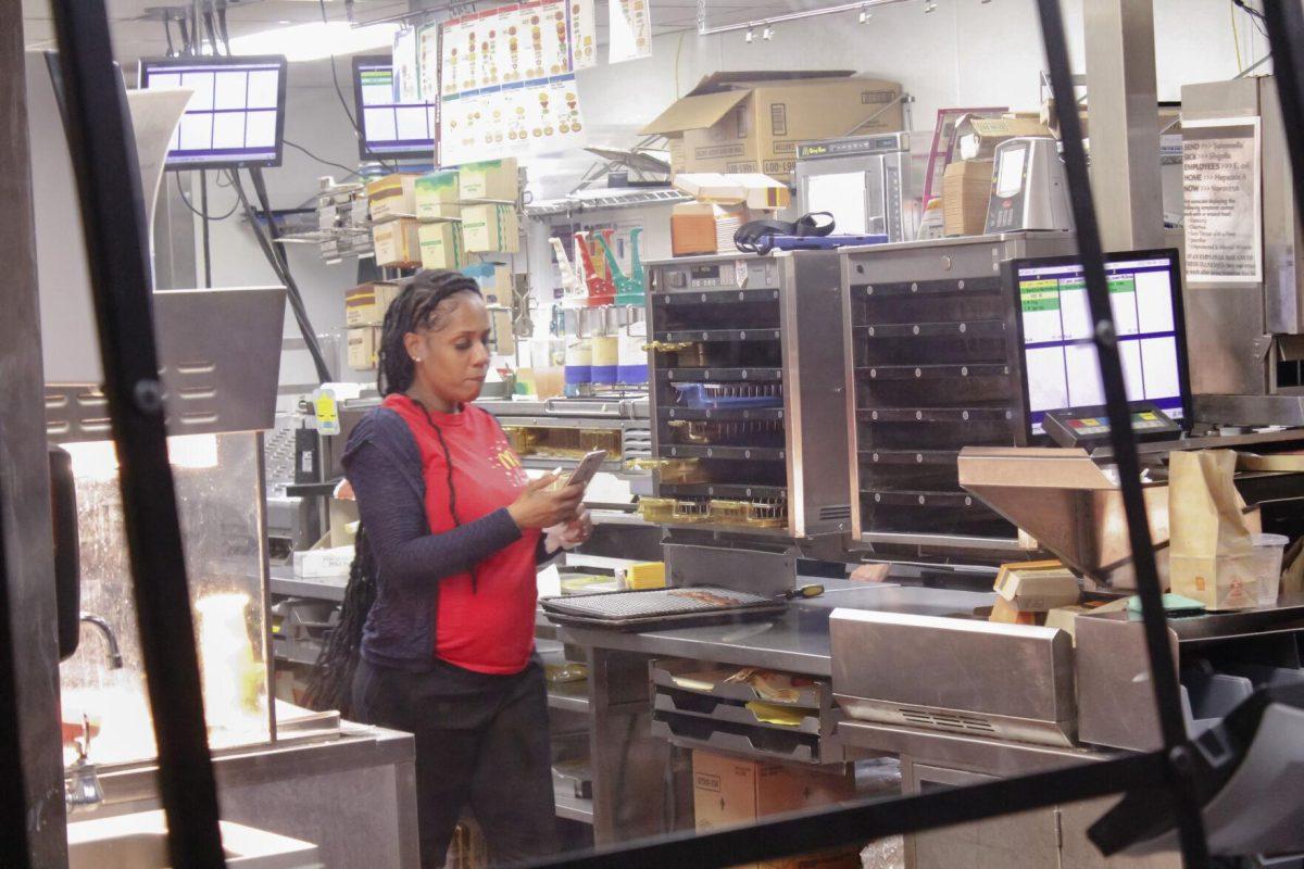 A McDonald's worker checks her phone in between orders on Friday, April 8, 2022, at the LSU Student Union in Baton Rouge, La.