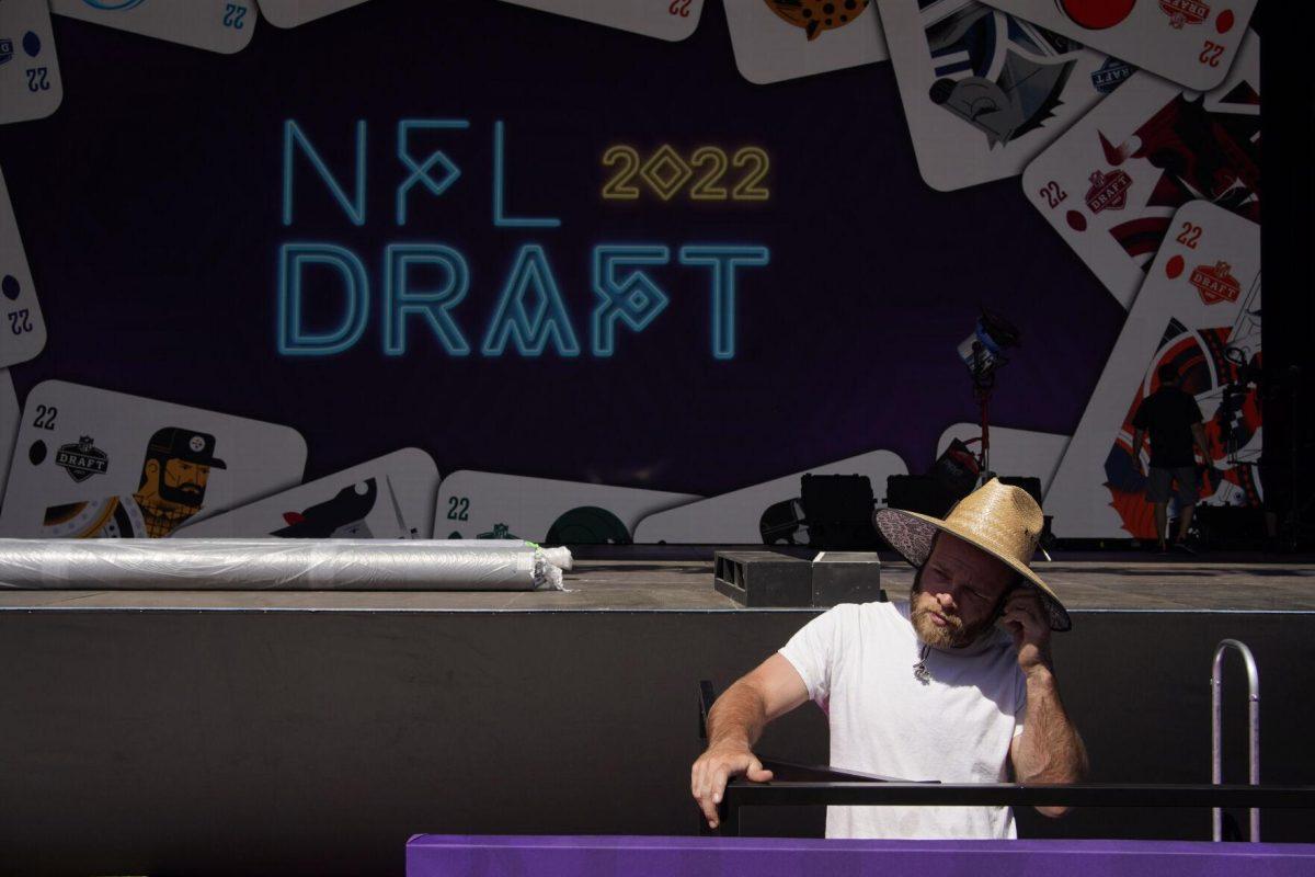 A worker helps erect a red carpet and stage in front of the Bellagio hotel-casino during setup for the NFL football draft Tuesday, April 26, 2022, in Las Vegas. (AP Photo/John Locher)