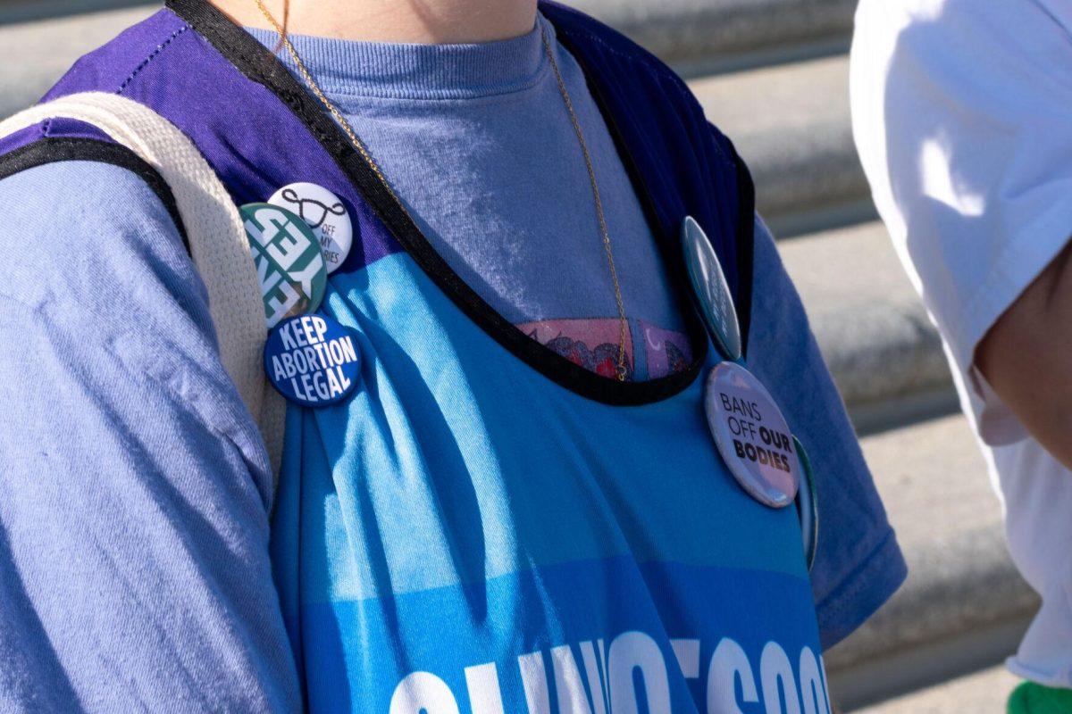 A student wears pro-choice pins on her clinic-escort vest.