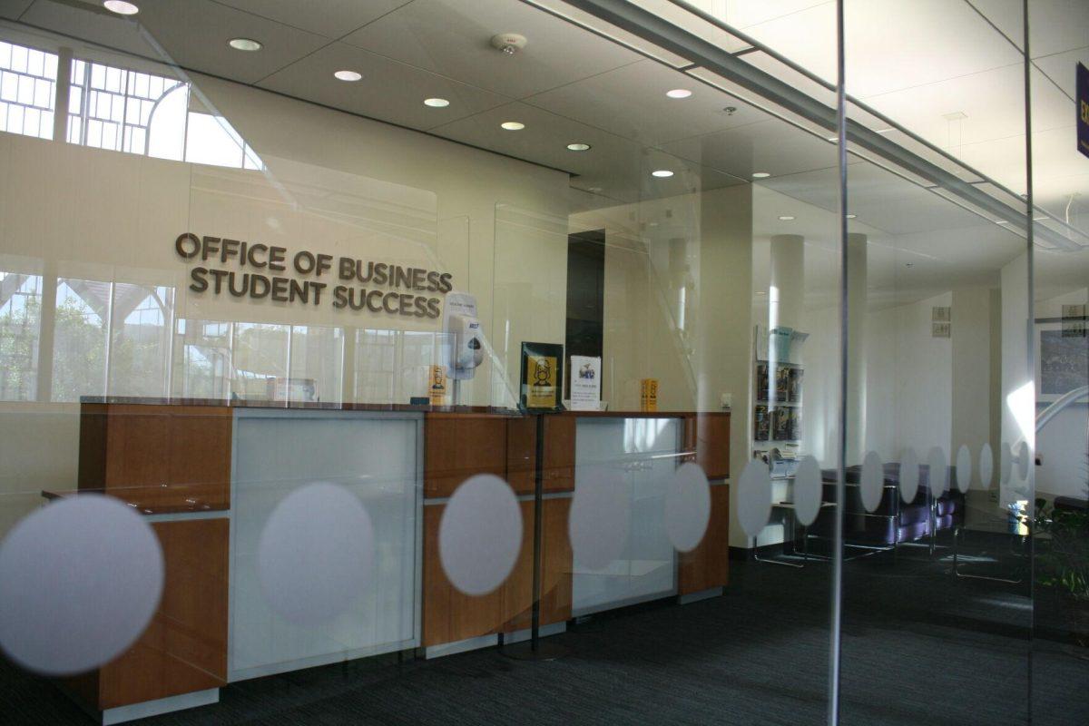 Masking signs stand in front of the desk of the Business Education Complex's Office of Business Student Success on Wednesday, May 18, 2022.