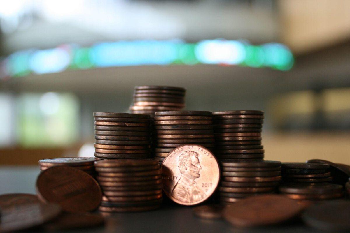 A pile of pennies collectively valued around $1.50 sits in front of the Business Education Complex's stock ticker on Friday, July 1, 2022.