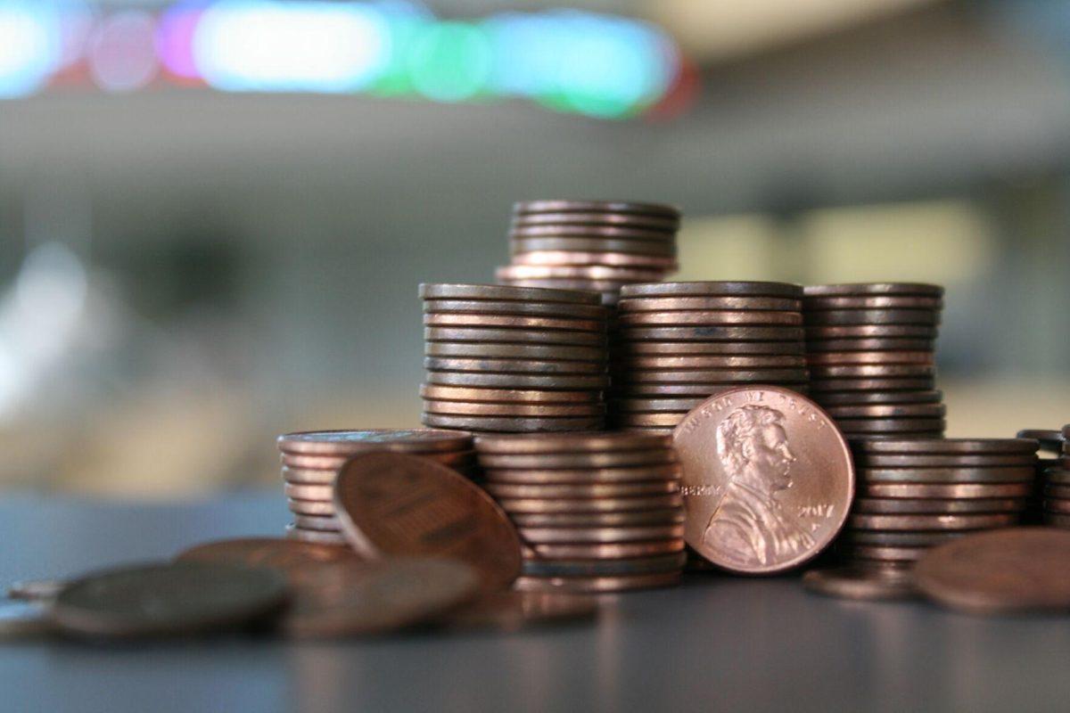 A pile of pennies collectively valued around $1.50 sits in front of the Business Education Complex's stock ticker on Friday, July 1, 2022.