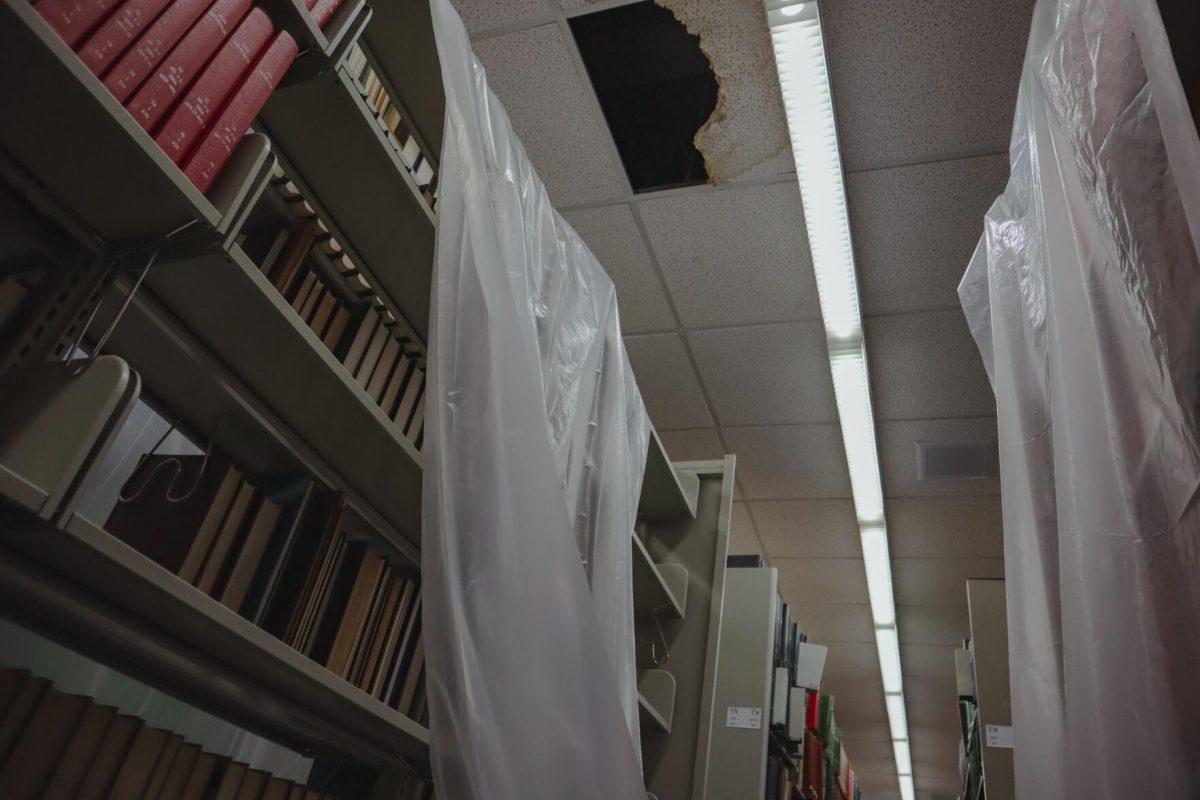 A hole appears in the ceiling tiles above tarped bookshelves on Tuesday, Aug. 30, 2022, inside of the LSU Library on Tower Drive in Baton Rouge, La.