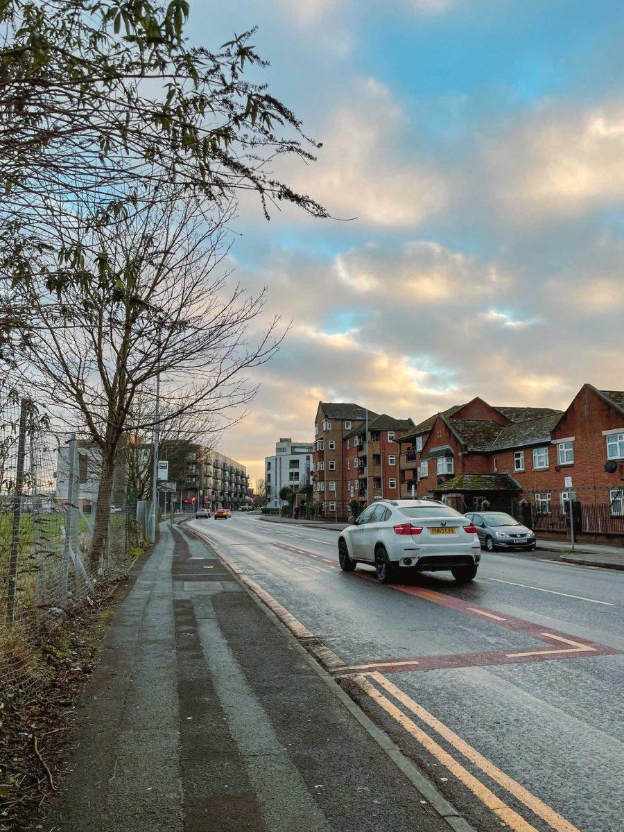 A car rushes down a cloud-framed street in Manchester, U.K.