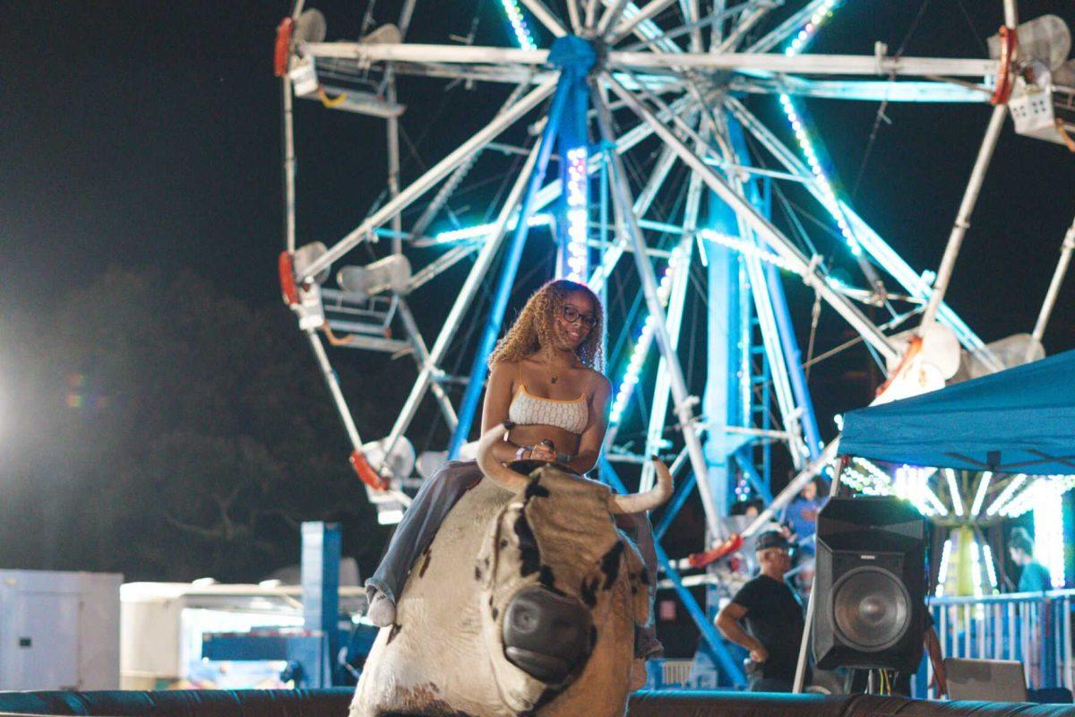 LSU animal science freshman Jaelyn Pickering rides a mechanical bull on Saturday, Aug. 20, 2022, at the Welcome Week Carnival near Tiger Stadium on South Stadium Drive in Baton Rouge, La.