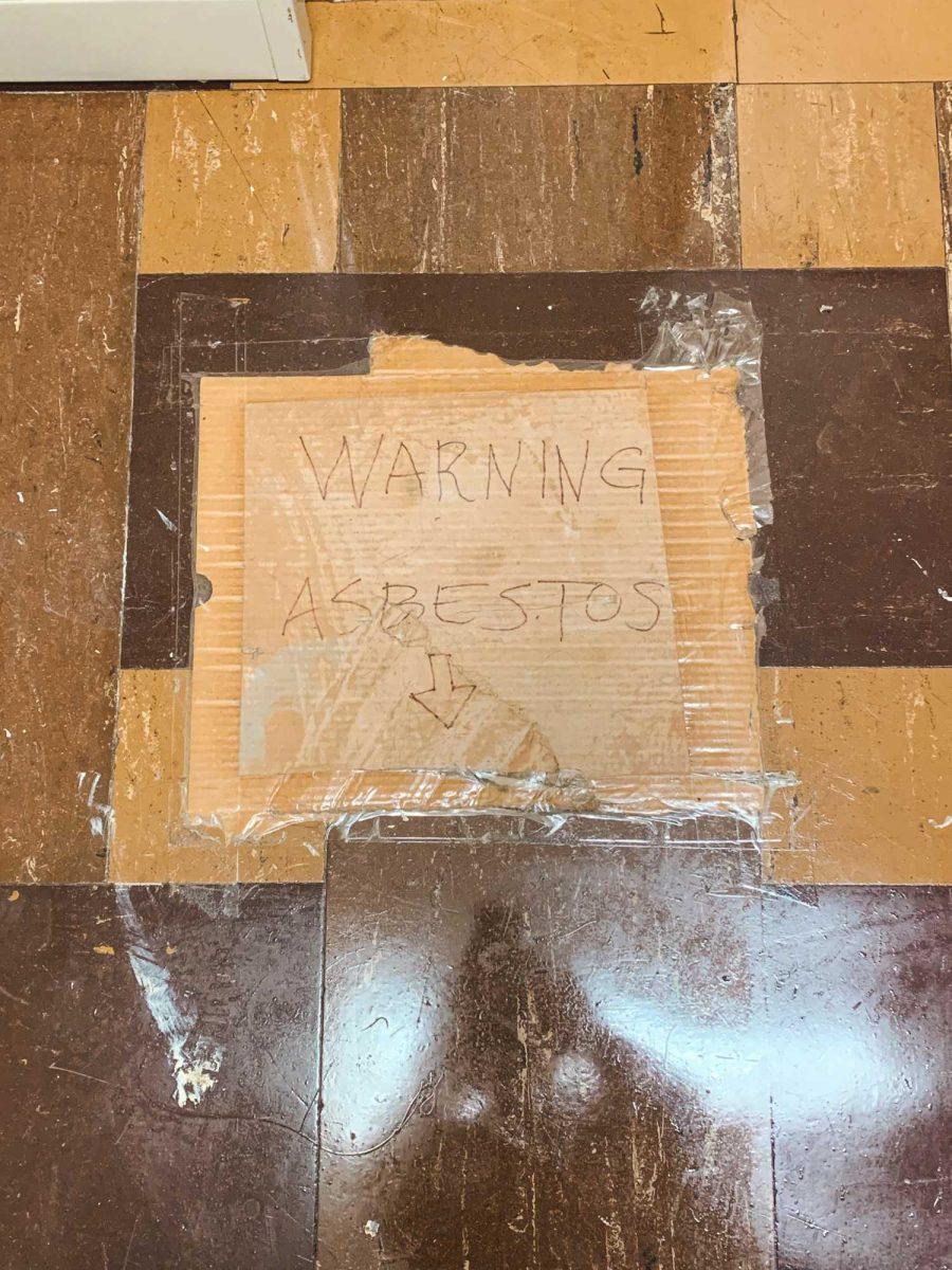 A cardboard sign marked with "WARNING: ASBESTOS" covers the floor in Himes Hall during the fall 2020 semester.