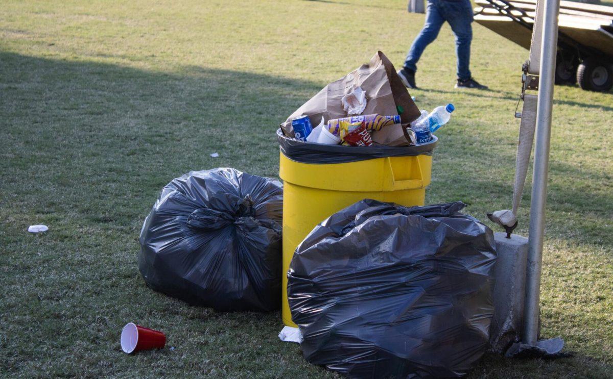 Two large garbage bags sit next to a trash can on the LSU Parade Ground after tailgating on Saturday, Sept. 24, 2022, in Baton Rouge, La.