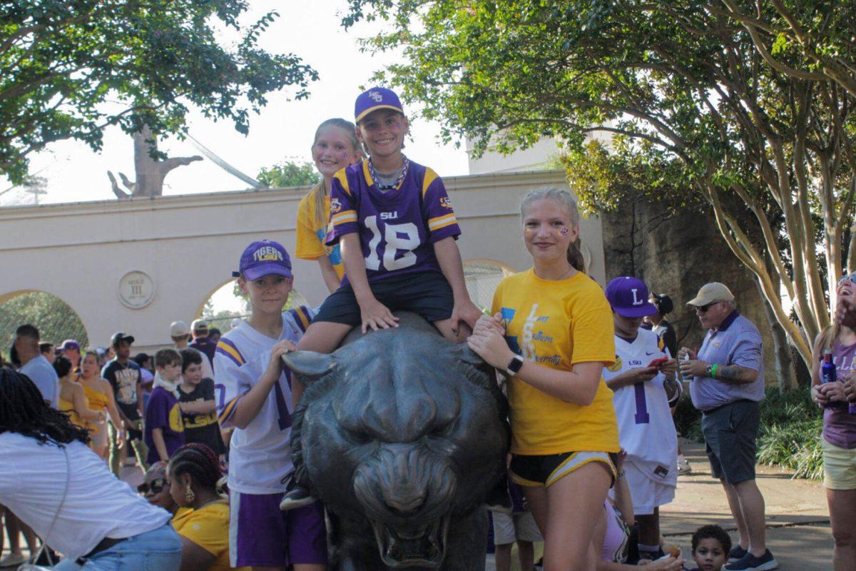 A group of siblings pose for a picture with the Mike the Tiger Statue on Saturday, Sept. 10, 2022, on N. Stadium Drive, in Baton Rouge, La.