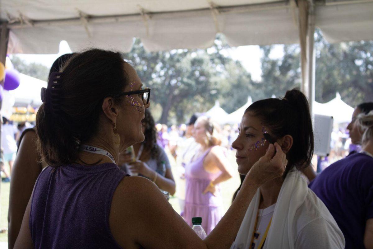 A woman applies face glitter at the LSU Family Weekend Tailgate on Saturday, Sept. 24, 2022, on the LSU Parade Ground in Baton Rouge, La.