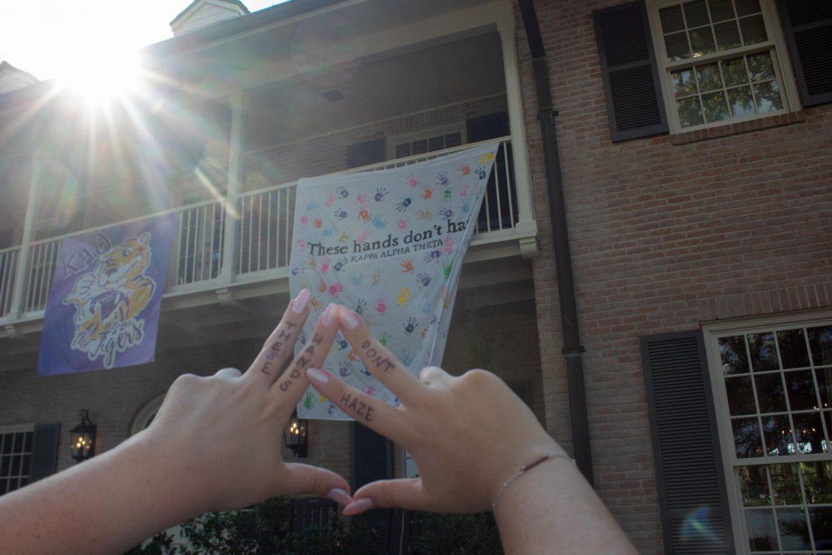 Junior LSU student Laine Cohen's hands hold up sorority hand sign in front of Kappa Alpha Theta house and banner on Thursday, Sept. 22, 2022 on W Lakeshore Drive in Baton Rouge.