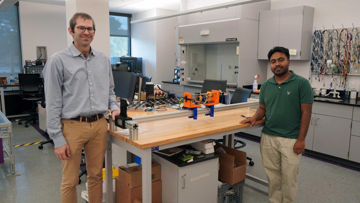 Mechanical engineering professor Hunter Gilbert, left, and mechanical engineering graduate student Shahrior Ahmed, right, stand with the prototype of their Center for Innovations in Structural Integrity Assurance-funded&#160;mechanical arm project in a lab in Patrick F. Taylor Hall.