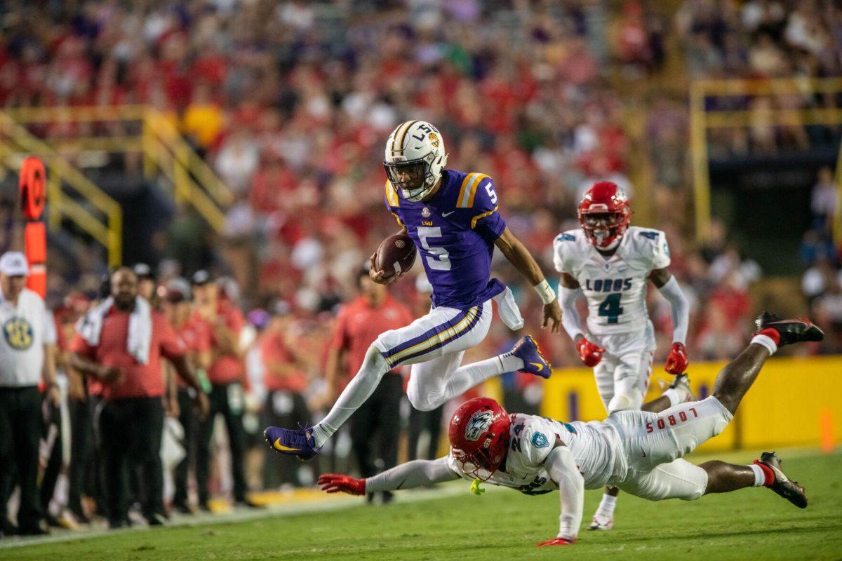 LSU football junior quarterback Jayden Daniels (5) jumps over an opposing player on Saturday, Sept. 24, 2022, during the LSU vs New Mexico game in Tiger Stadium&#160;in Baton Rouge, La.