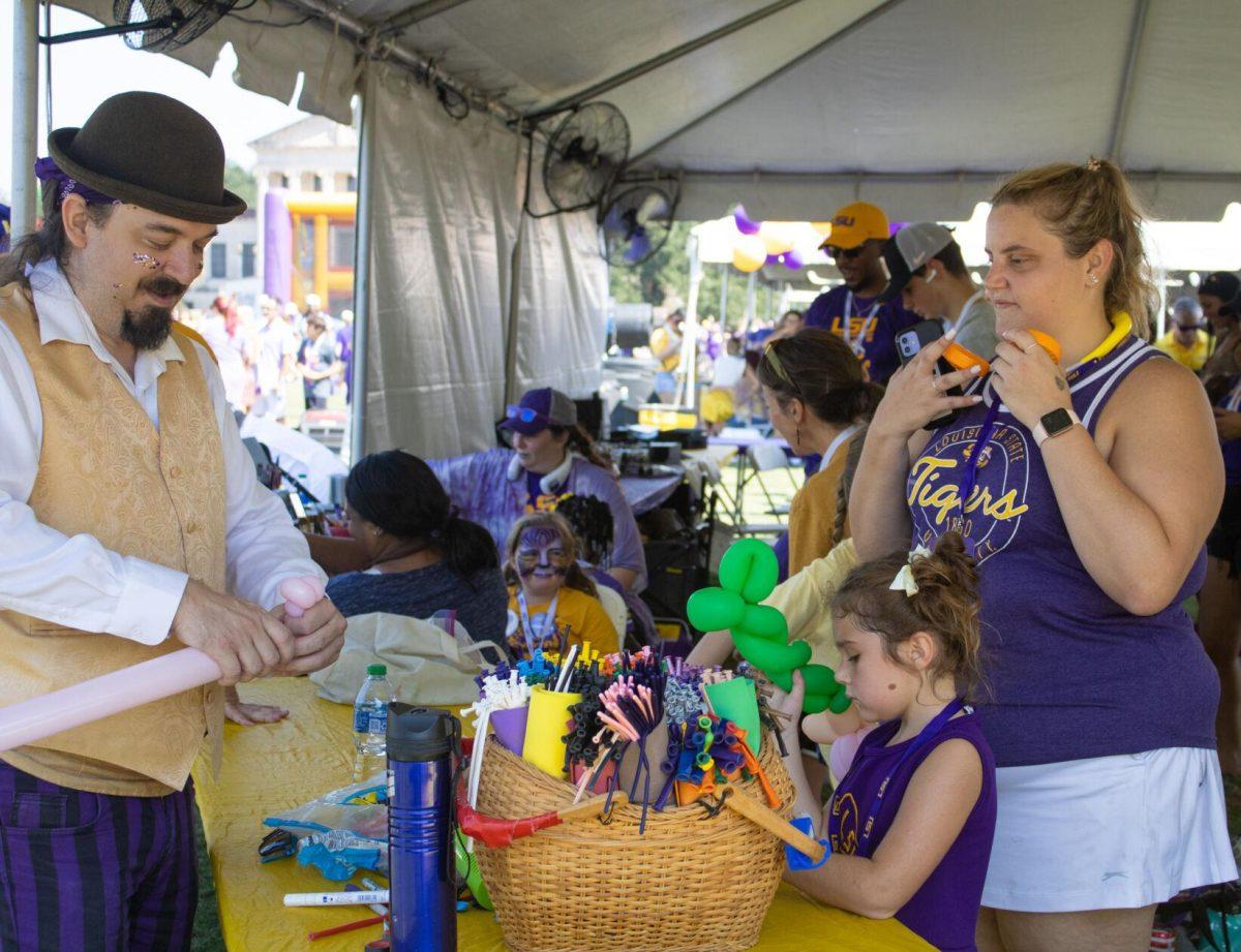 A family waits in line for a balloon animal at the LSU Family Weekend Tailgate on Saturday, Sept. 24, 2022, on the LSU Parade Ground in Baton Rouge, La.