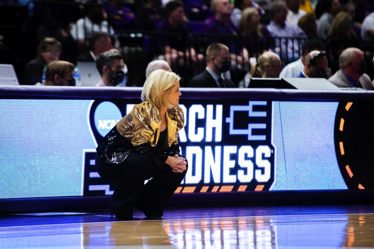 LSU women&#8217;s basketball head coach Kim Mulkey squats in front of the "March Madness" sign Saturday, March 19, 2022, during LSU&#8217;s 83-77 win against Jackson State in the first round of the NCAA women&#8217;s basketball tournament in the Pete Maravich Assembly Center on North Stadium Drive in Baton Rouge, La.