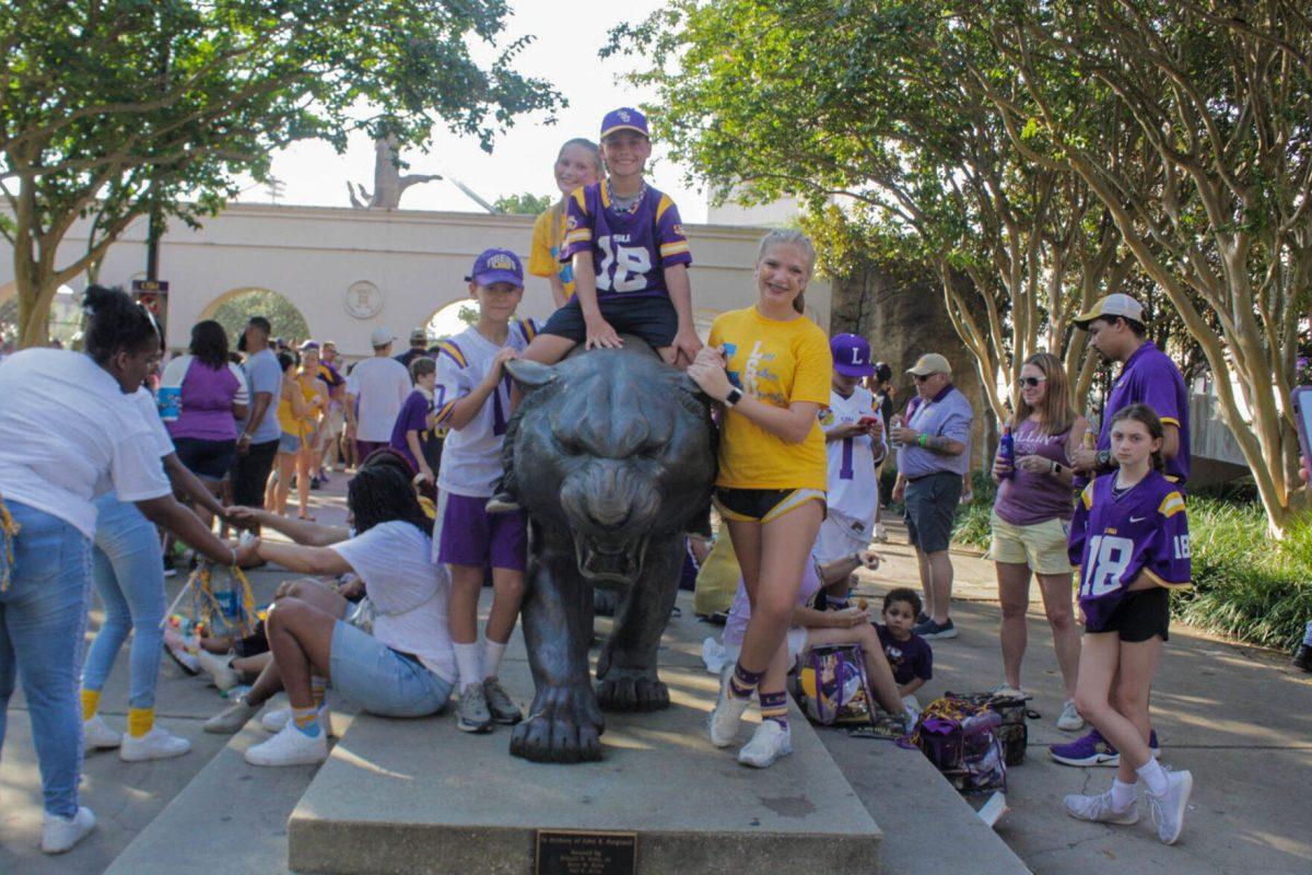 A group of siblings pose for a picture with the Mike the Tiger Statue on Saturday, Sept. 10, 2022, on N. Stadium Drive, in Baton Rouge, La.