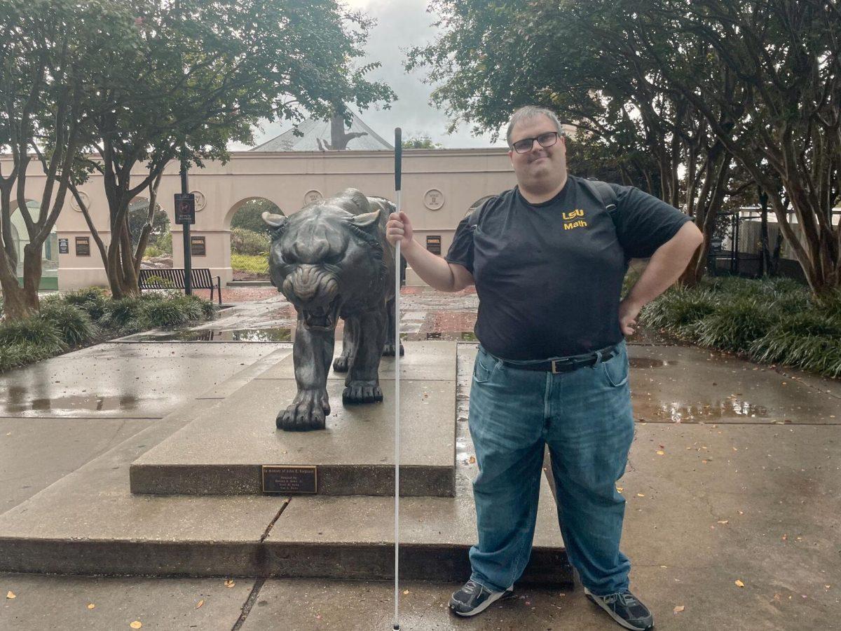 LSU graduate student Justin Champagne poses on Friday, Sept. 9, 2022, next to a Mike the Tiger statue on North Stadium Drive in Baton Rouge, La.