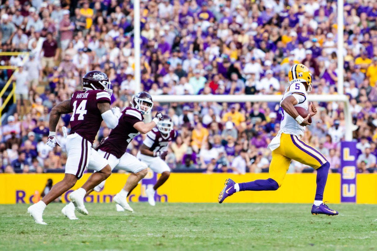 LSU football junior quarterback Jayden Daniels (5) scrambles from two Mississippi State players Saturday, Sept. 17, 2022 during LSU’s 31-16 win against Mississippi State at Tiger Stadium in Baton Rouge, La.
