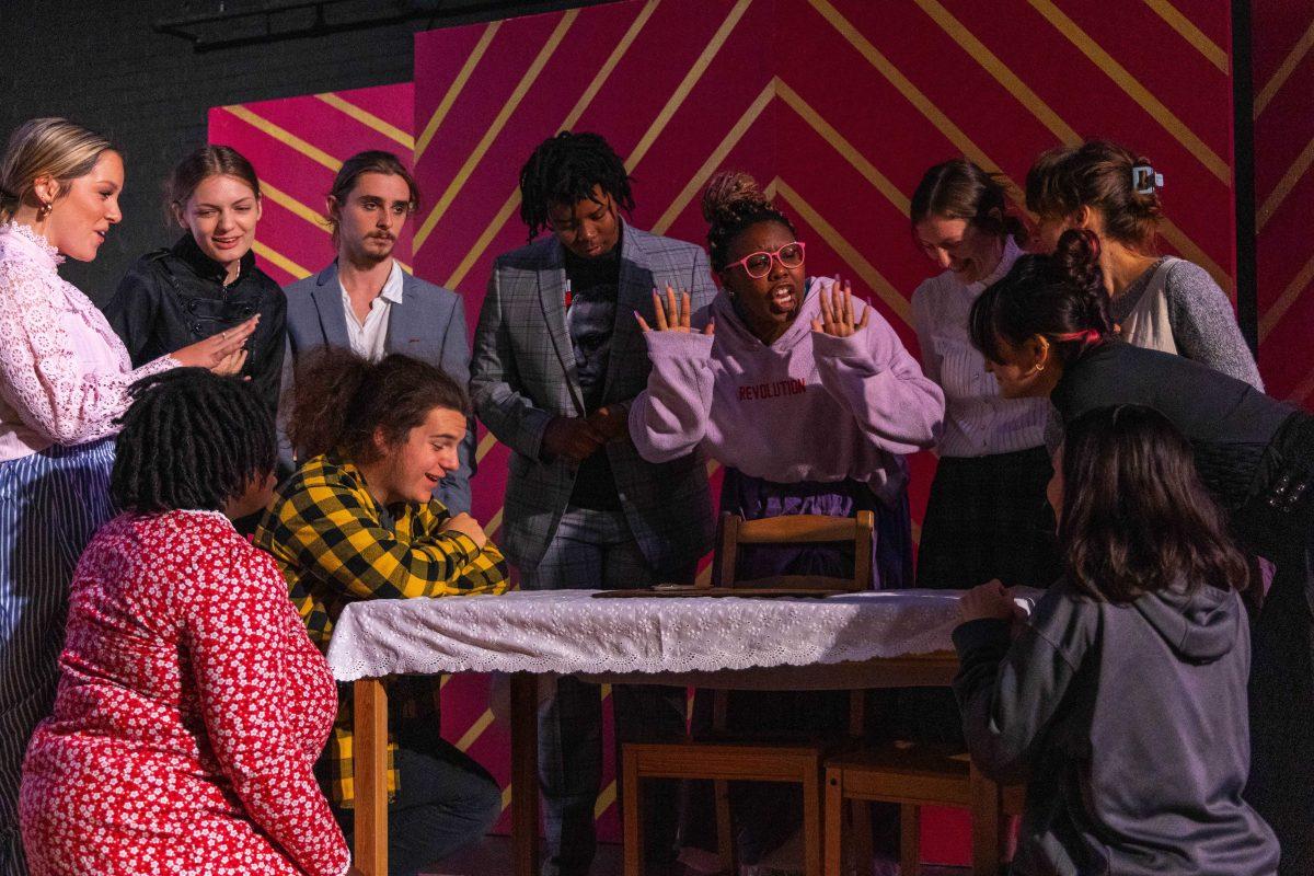 Cast members gather around the table to see a demonstration of how the Ouija board works Thursday, Oct. 20, 2022, during the dress rehearsal for "In the Spirit of Twain" in the HopKins Black Box Theater in Coates Hall.