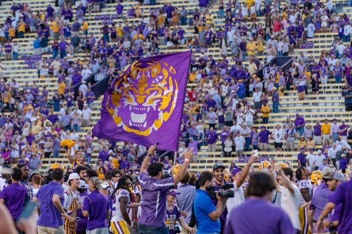 An LSU flag flies over LSU fans on the field on Saturday, Oct. 22, 2022, after LSU&#8217;s 45-20 victory over Ole Miss in Tiger Stadium in Baton Rouge, La.