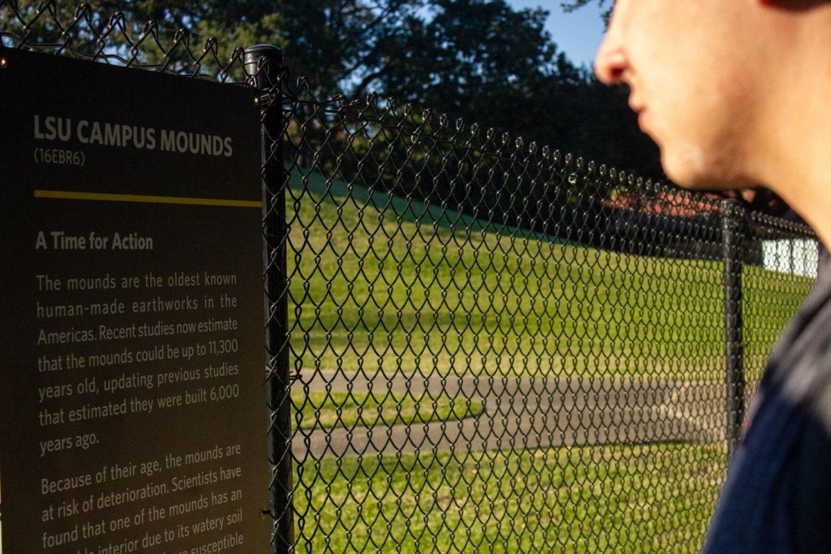 A student reads the sign on Monday, Sept. 26, 2022, in front of the LSU campus mounds in Baton Rouge, La.