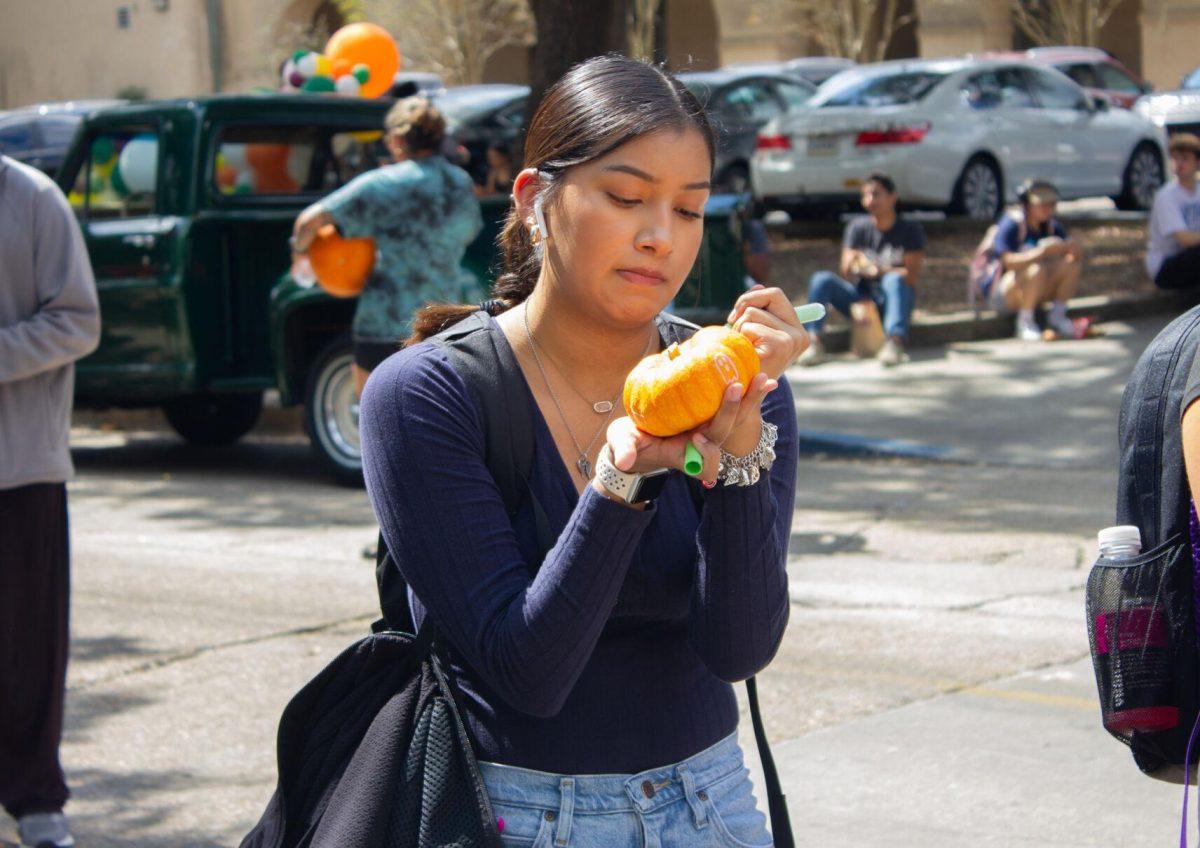 An LSU student draws on the miniature pumpkin on Wednesday, Oct. 5, 2022, on Tower Drive in Baton Rouge, La.