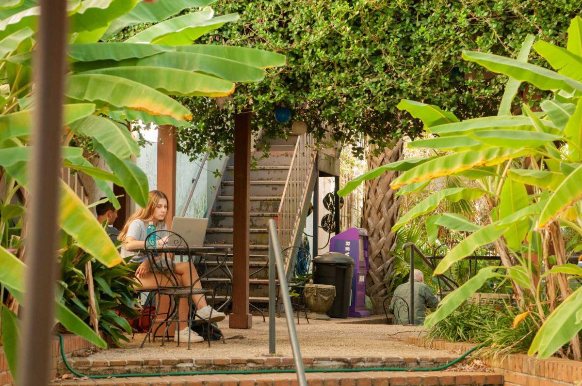 A young woman scrolls on her laptop in the courtyard&#160;on Saturday, Oct. 1, 2022,&#160;at Highland Coffees on Highland Road in Baton Rouge, La.