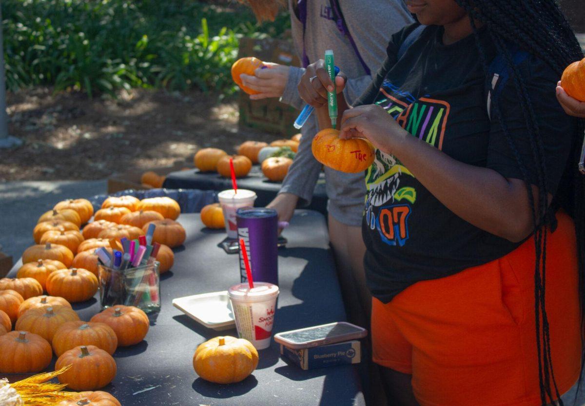 LSU students draw on miniature pumpkins on Wednesday, Oct. 5, 2022, on Tower Drive in Baton Rouge, La.