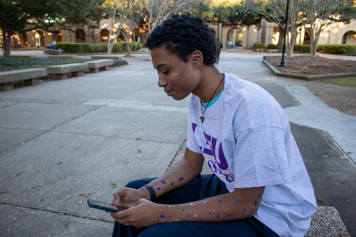 Sophomore student Jahbari Parquet plays his phone on Sunday, Nov. 20, 2022, in the quad on LSU's campus.