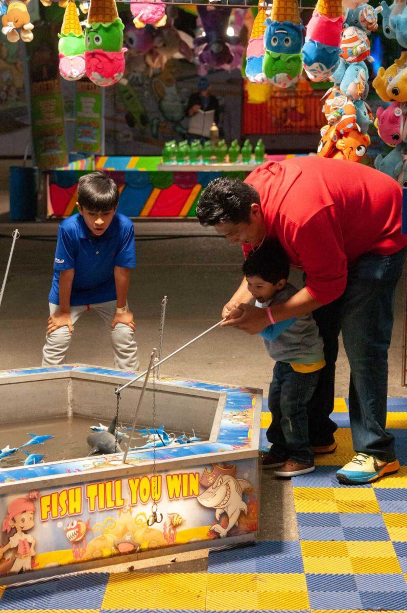 A child fishes for toy sharks with his father's help and his older brother's encouragement at the Greater Baton Rouge State Fair on Sunday, Oct. 30, 2022, at the Lamar Dixon Expo Center in Gonzales, La.