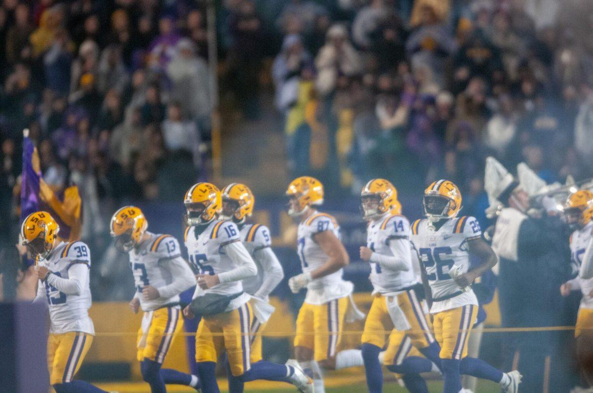 The LSU Football team players runs through the smoke from the cannons during pregame on Saturday, Nov. 19, 2022, inside Tiger Stadium in Baton Rouge, La.