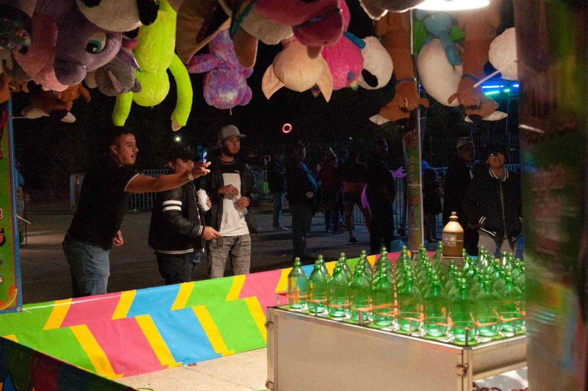 Three adult men compete in a ring toss at the Greater Baton Rouge State Fair on Sunday, Oct. 30, 2022, at the Lamar Dixon Expo Center in Gonzales, La.