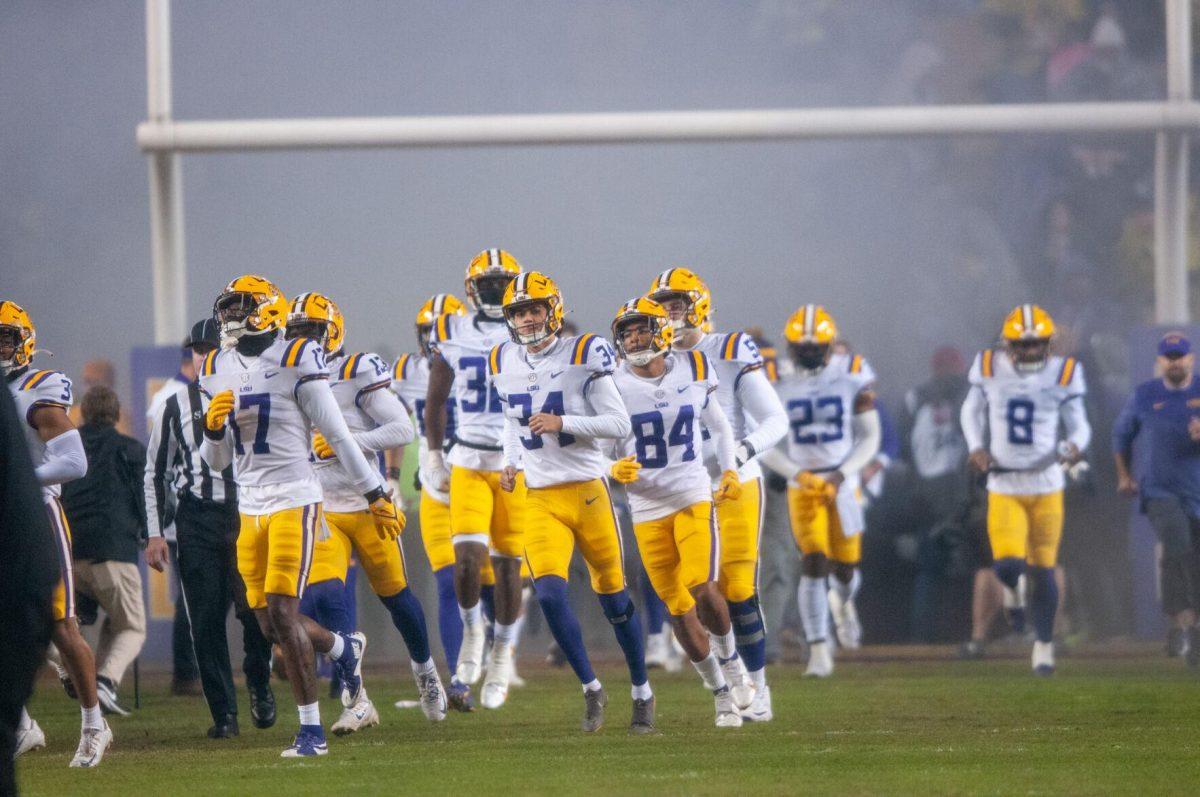 The LSU football team runs onto the field through the smoke during pregame on Saturday, Nov. 19, 2022, inside Tiger Stadium in Baton Rouge, La.