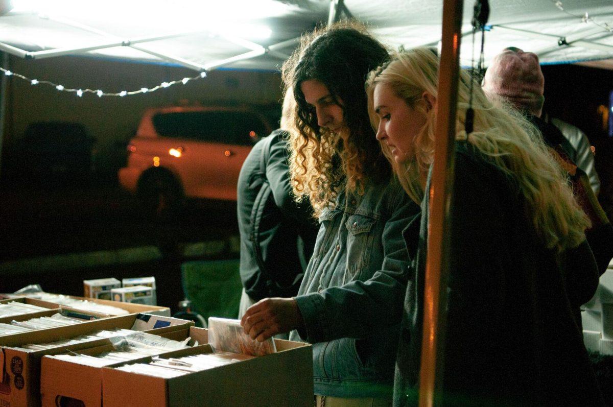 A young man and woman browse through artwork prints on Friday, Nov. 18, 2022, at Mid City Merchant's White Light Night on Government Street in Baton Rouge, La.