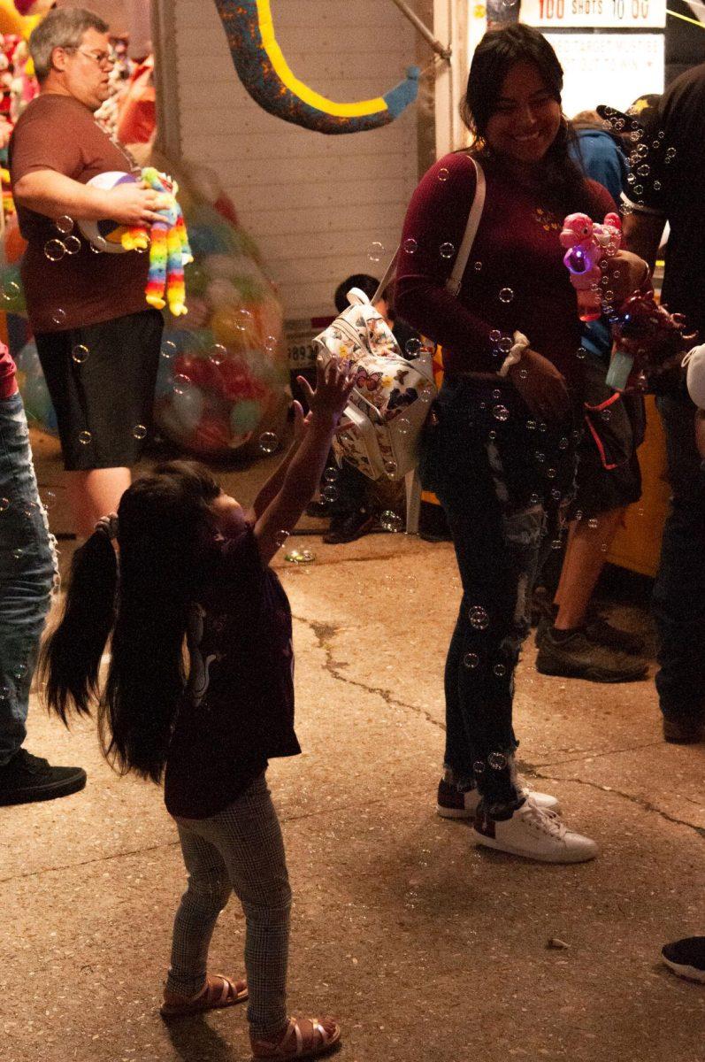 A mom smiles at her young daughter who reaches for bubbles at the Greater Baton Rouge State Fair on Sunday, Oct. 30, 2022, at the Lamar Dixon Expo Center in Gonzales, La.