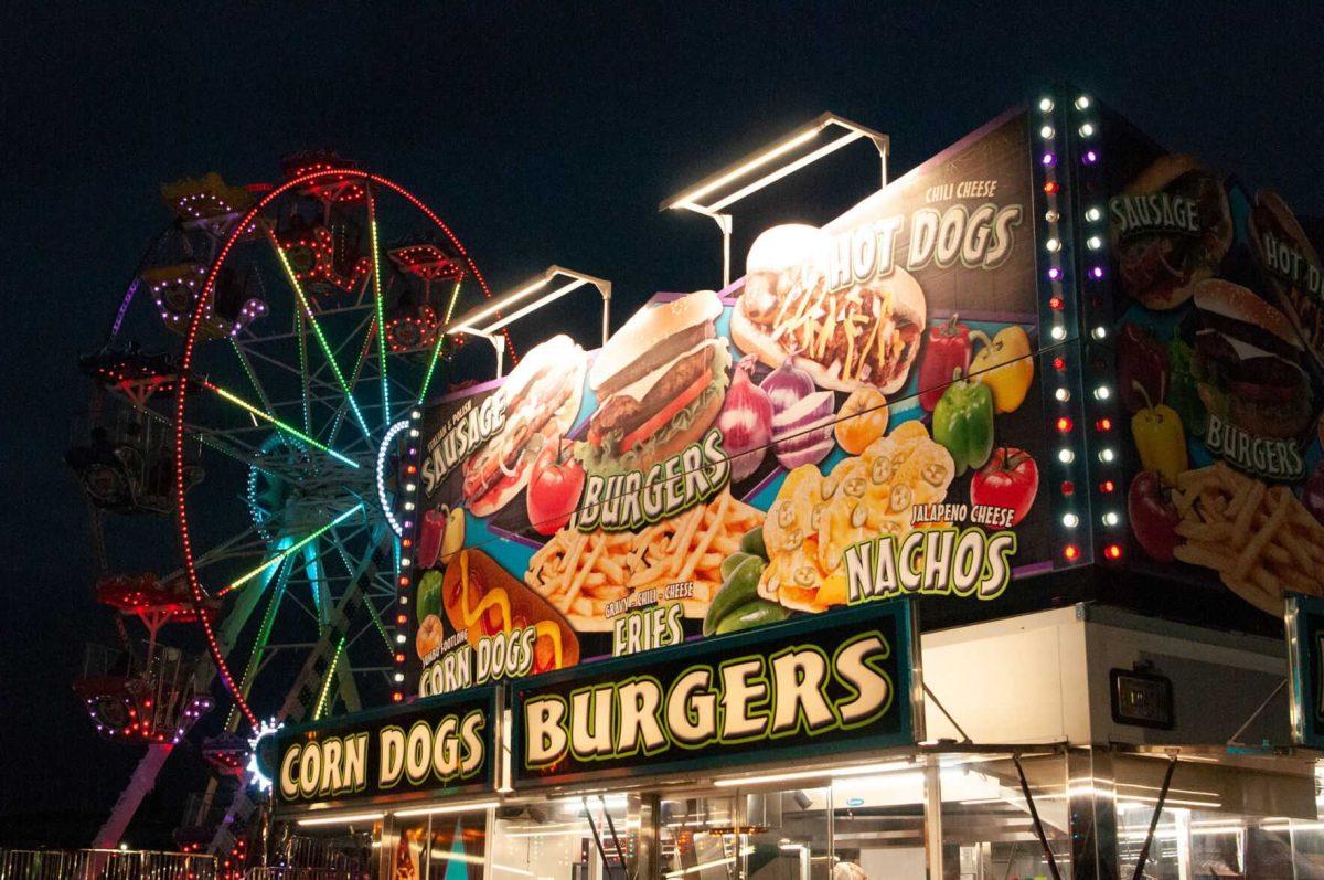 A food vendor structure glows at night in front of a Ferris wheel at the Greater Baton Rouge State Fair on Sunday, Oct. 30, 2022, at the Lamar Dixon Expo Center in Gonzales, La.