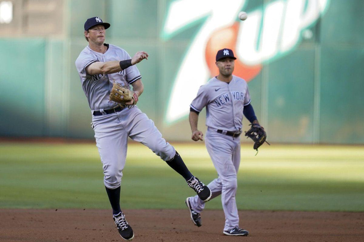 New York Yankees shortstop Isiah Kiner-Falefa, background, watches as second baseman DJ LeMahieu, left, throws to first base for an out against Oakland Athletics' Shea Langeliers during the first inning of a baseball game in Oakland, Calif., Saturday, Aug. 27, 2022. (AP Photo/Godofredo A. V&#225;squez)