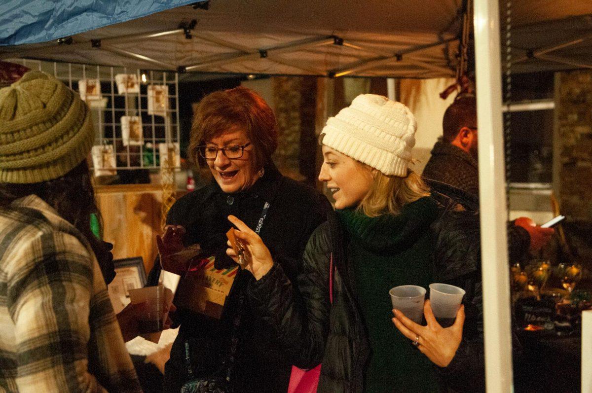 Three women discuss their purchases on Friday, Nov. 18, 2022, at Mid City Merchant's White Light Night on Government Street in Baton Rouge, La.