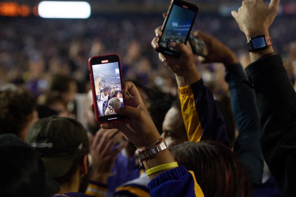 A fan catches defensive end Quincy Wiggins on his phone camera after rushing the field on Saturday, Nov. 5, 2022, during LSU&#8217;s 32-31 victory over Alabama in Tiger Stadium in Baton Rouge, La.