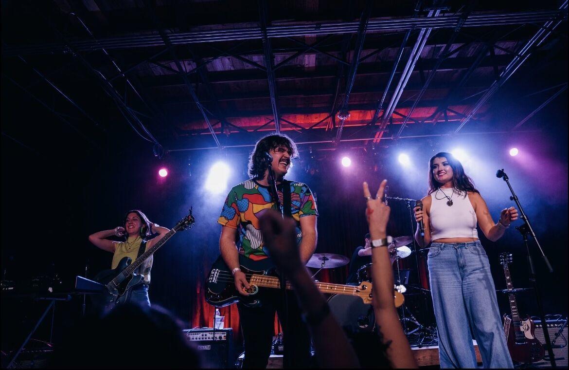 Speak Easy rhythm guitarist Katelyn Chopin and singer Madison Delacroix stand near bassist John Bajor as Speak Easy performs live.