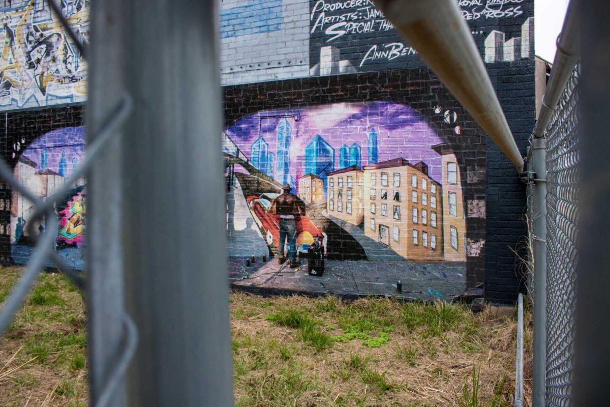 An eye-catching mural hides behind a fence on Friday, Dec 2, 2022, in downtown Baton Rouge, La.