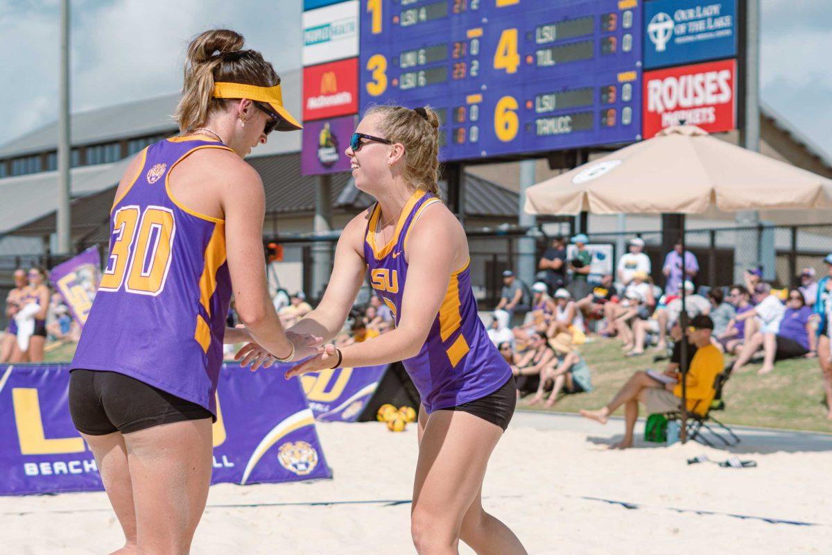 LSU beach volleyball graduate student Hannah Brister (30) and freshman Ella Larkin (3) high-five on Sunday, March 6, 2022, during LSU&#8217;s 3-2 win over Loyola Marymount at the Beach Volleyball Stadium on Cypress Drive in Baton Rouge, La.