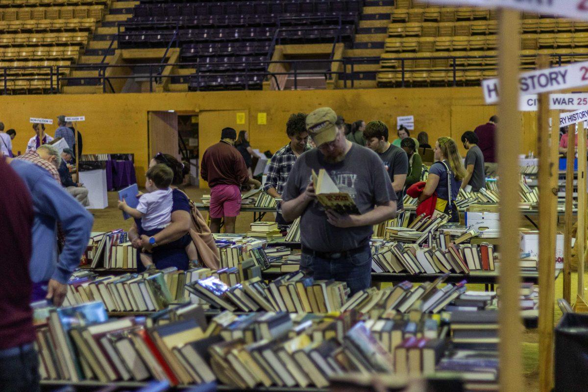 A visitor reads through a book Sunday, March 20, 2022, at the annual Book Bazaar that took place in the John M Parker Agricultural Coliseum on LSU's campus.