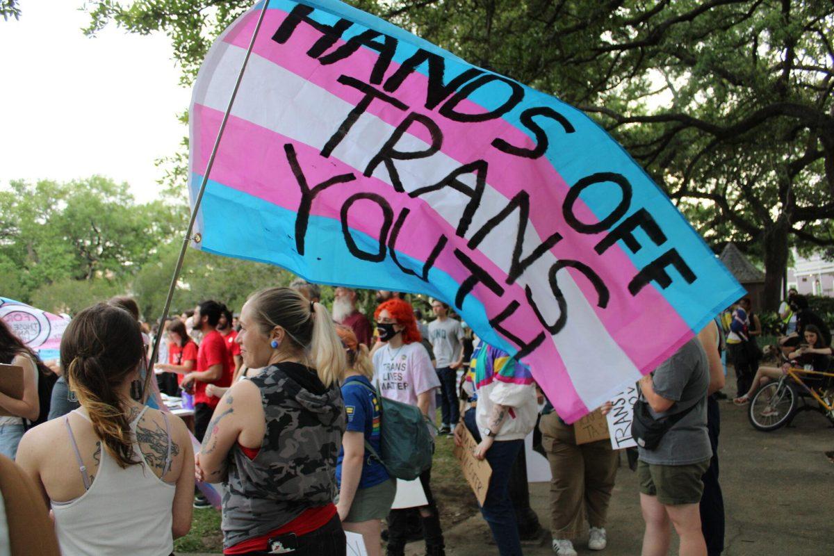 A transgender Pride flag is covered with the words &#8220;Hands Off Trans Youth.&#8221; Hundreds of people gathered Friday, March 31, 2023, at Washington Square Park in New Orleans for a march to mark Transgender Day of Visibility.