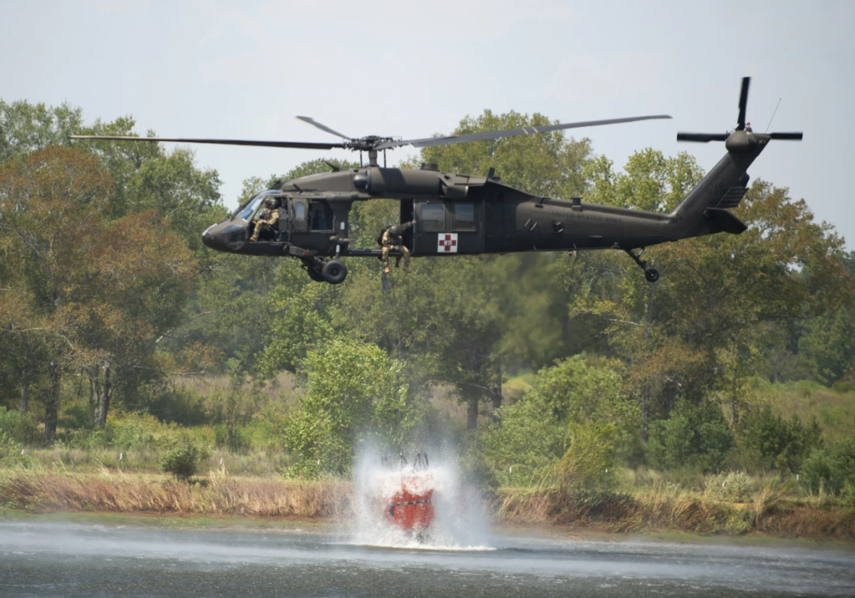 A Blackhawk helicopter fills a 660-gallon basket of water from a farm pond to help battle a wildfire, Thursday, Aug. 24, in Beauregard Parish, La.