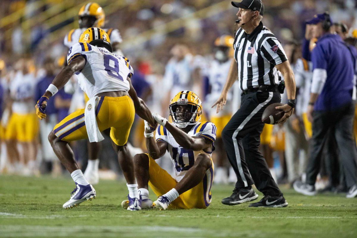 LSU football junior safety Major Burns (8) helps sophomore cornerback Denver Harris (10) up Saturday, Sept. 23, 2023, during LSU's 34-31 win against Arkansas at Tiger Stadium in Baton Rouge, La.