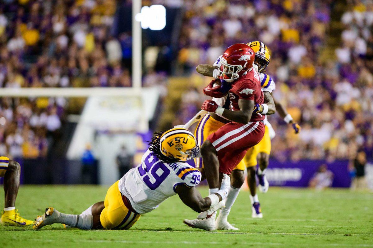 LSU football senior defensive tackle Jordan Jefferson (99) and senior safety Andre' Sam (14) tackle their opponent on Saturday, Sept. 23, 2023, during LSU's 34-31 victory over Arkansas in Death Valley in Baton Rouge, La.