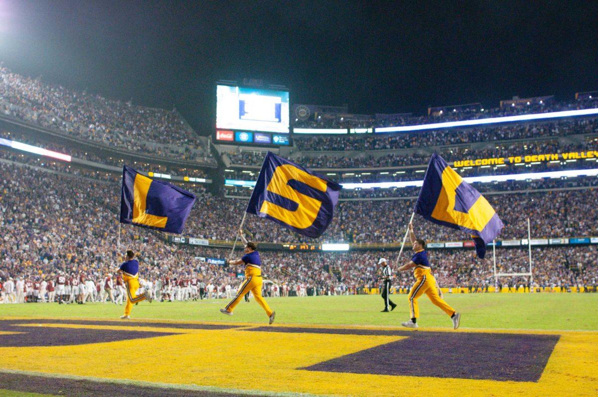 LSU cheerleaders sprint across the end zone with "LSU" flags on Saturday, Nov. 5, 2022, during LSU&#8217;s 32-31 victory over Alabama in Tiger Stadium in Baton Rouge, La.